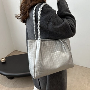 Sac cabas argenté à motif pied-de-poule avec anses tressées porté par un mannequin élégant