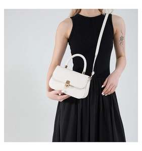 Detail of off-white leather handbag with gold twist lock and circular top handle