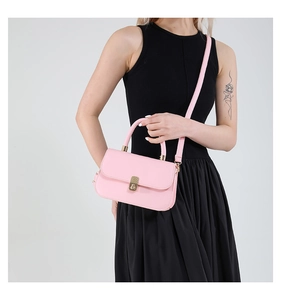 Detailed view of pink leather baguette bag with gold twist lock on black dress