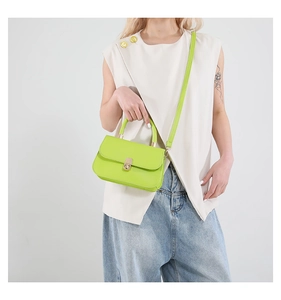 Detail of lime green faux leather small square bag with golden twist lock on model