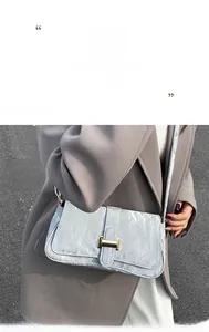 Detail of light blue marble textured baguette bag with a golden H-shaped buckle