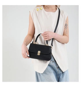 Minimalist black leather handbag with gold twist lock shown on a model for daily styling