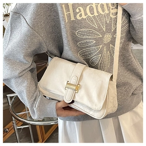 Detail of a creamy white leather baguette bag with a sleek gold-tone metal buckle