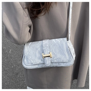 Detail of light blue wrinkled leather baguette bag with a golden H-shaped clasp