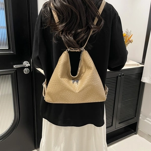 Minimalist khaki woven leather backpack for women with a silver butterfly emblem detail