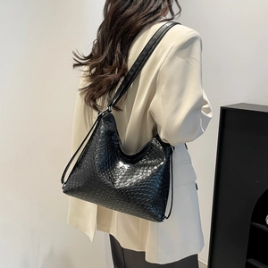 Fashionable black woven tote backpack with large capacity worn by a model in a beige blazer