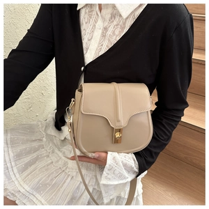 Detail view of beige saddle bag with gold metal clasp and premium synthetic leather
