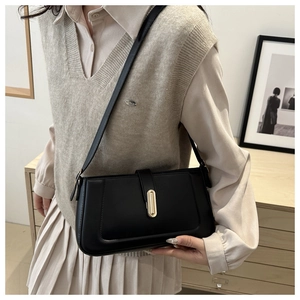 Detail of a black leather minimalist crossbody bag with elegant gold metal buckle closure