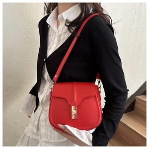 Close-up of saddle bag featuring red leather texture and golden twist lock hardware