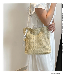 Detail of hand-woven straw tote with thick rope handles and striped silk ribbon accent