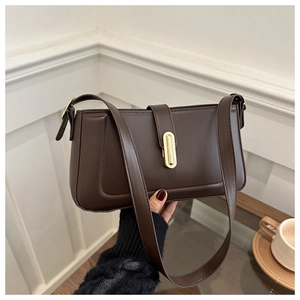 Detail of minimalist dark brown square bag with golden oval clasp and stitching