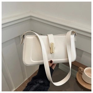 Detail of minimalist cream square bag featuring a gold bar buckle and wide shoulder strap
