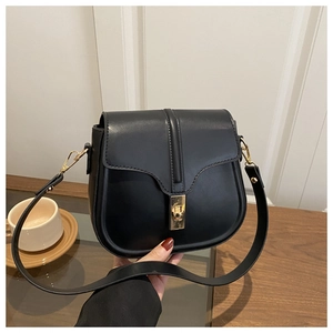 Detail of black matte leather saddle bag with signature golden metal twist-lock buckle