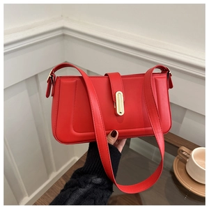 Detail of red minimalist square shoulder bag with gold metal lock and leather texture