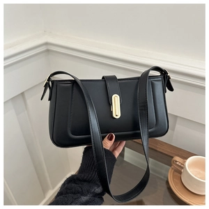 Detail of minimalist black baguette bag featuring U-shaped stitching and gold metal buckle