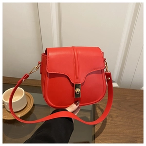 Detail of red leather saddle bag with gold metal clasp and U-shaped flap design