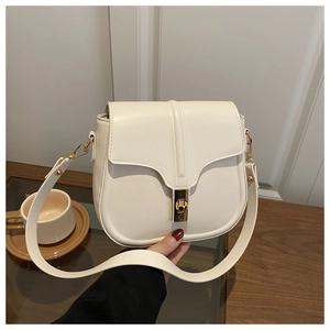 Detailed view of cream leather saddle bag with wavy flap and golden rotary metal lock