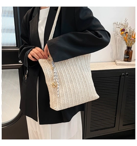 Detail of off-white straw woven tote bag featuring vertical knit textures and blue pendant