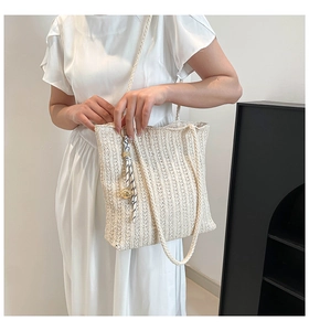 Close-up of cream woven straw tote bag with textured knit and striped scarf accessory