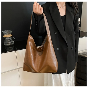 Detail of a large brown hobo tote bag in soft leather texture on a model shoulder