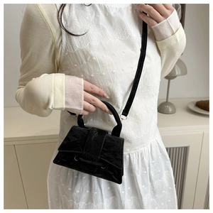 Close-up of a black textured mini tote bag with a curved base and elegant top handle