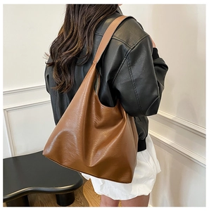 Detailed view of caramel brown leather tote bag with soft texture and slouchy design