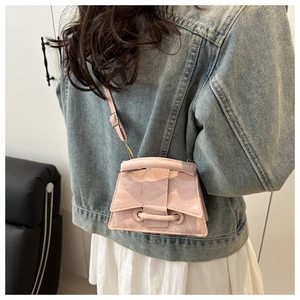 Rear view of a model wearing a light pink patent leather mini crossbody bag over denim jacket