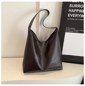 Macro view of dark brown tote bag showing textured synthetic leather and matte finish