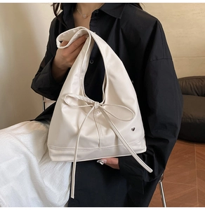 Detail of minimalist cream tote bag with ribbon bow and silver heart pendant decoration