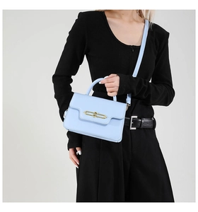 Detail view of light blue square crossbody bag with gold metal clasp and leather texture