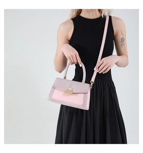 Details einer rosa Handtasche mit Krokodilmuster, Pailletten und goldener Metallschnalle
