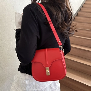 Classic red saddle shoulder bag with gold square buckle shown on model in home setting