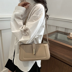 Chic beige leather underarm bag with gold metal clasp on a stylish female model