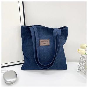 Detail of blue denim tote bag with leather tag, silver headphones and tulips decor