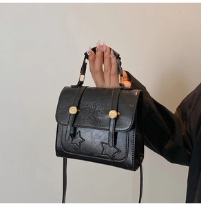 Detail of black matte PU leather mini square bag with embossed letters and star stitching