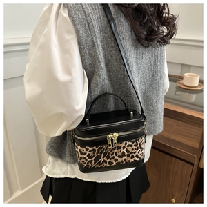 Sac boîte léopard porté par un mannequin avec zips dorés et bandoulière en cuir noir