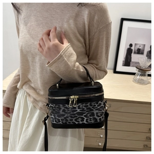 Détail du sac léopard avec fermetures dorées et poignée supérieure en cuir noir