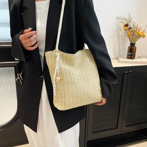 Sac fourre-tout en paille tressée beige avec anse en corde et ruban sur modèle