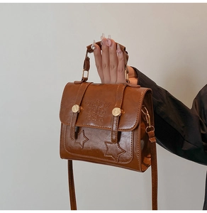 Detail of a brown PU leather vintage crossbody bag with star embossing and metal clasp