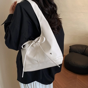 Solid color hobo tote bag with bow detail and silver heart pendant on model