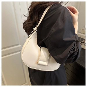 White crescent leather shoulder bag shown on shoulder against a black outfit backdrop