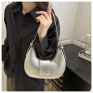 Close-up of matte silver crescent handbag with wide decorative strap and adjustable handle
