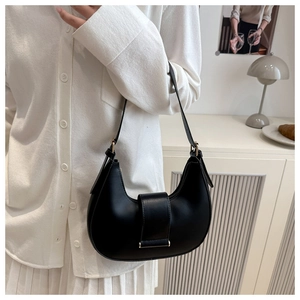 Detailed side view of a black leather crescent hobo bag worn by a model in a warm setting