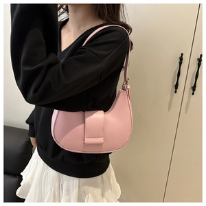 Pink crescent hobo bag made of smooth leather worn by a model in a minimalist setting