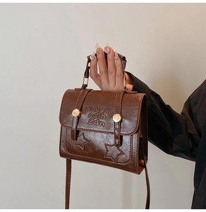 Detail of vintage brown leather handbag with embossed letters and star stitching