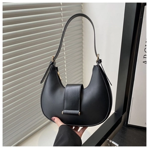 Detail of black crescent hobo bag featuring gold zipper and adjustable shoulder strap