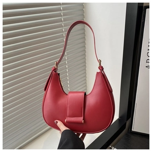 Detail view of the red half-moon handbag showing its matte texture and stitching