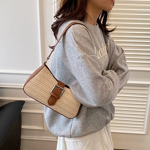 Woven straw underarm bag with brown leather trim and silver buckle for summer beach wear