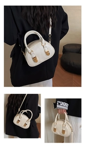 Detail view of a cream mini bowling bag featuring gold buckles and adjustable shoulder strap
