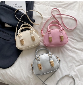 Detailed view of three mini shell bags in cream, pink and silver with gold hardware